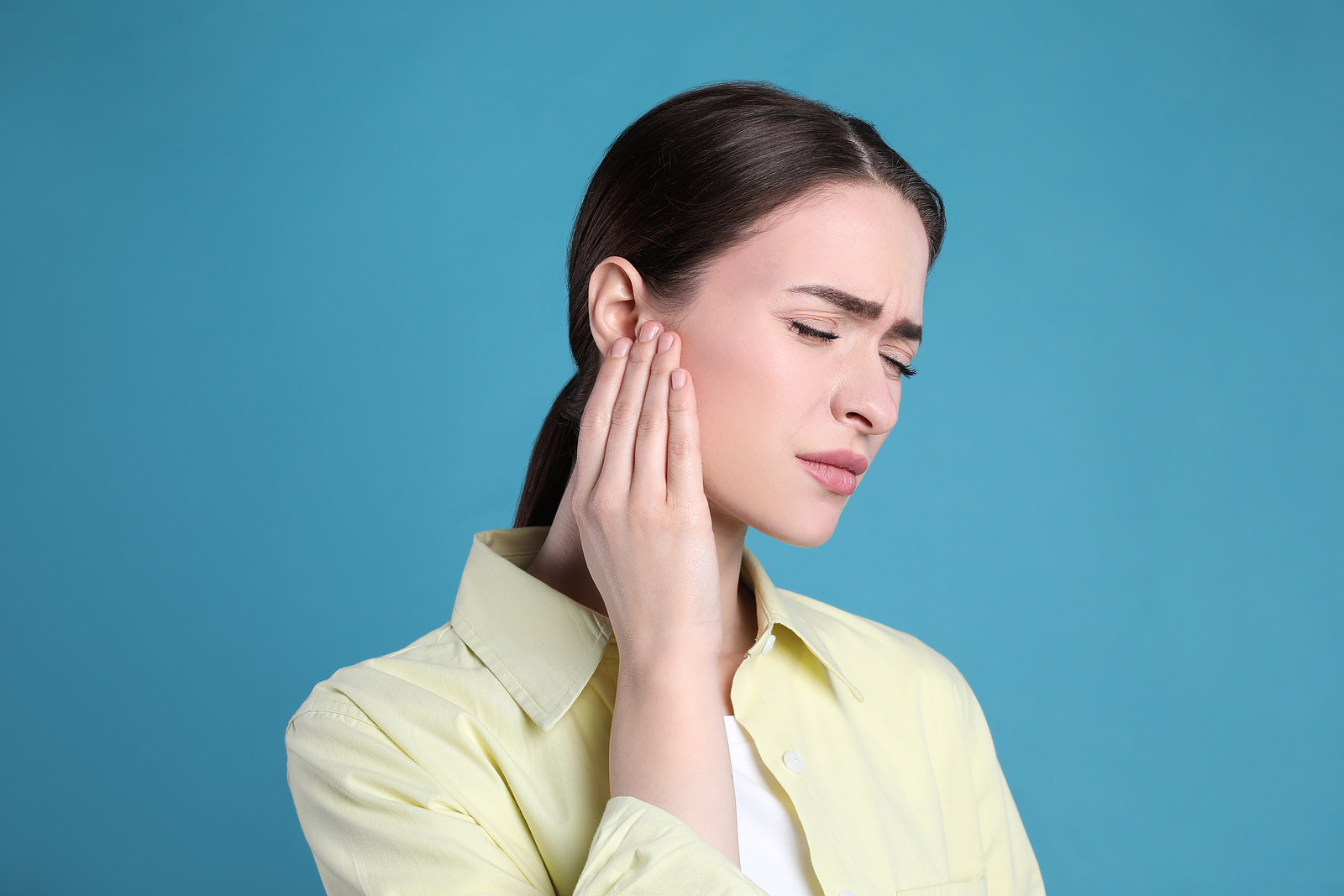 Woman holding hand up to ear in pain