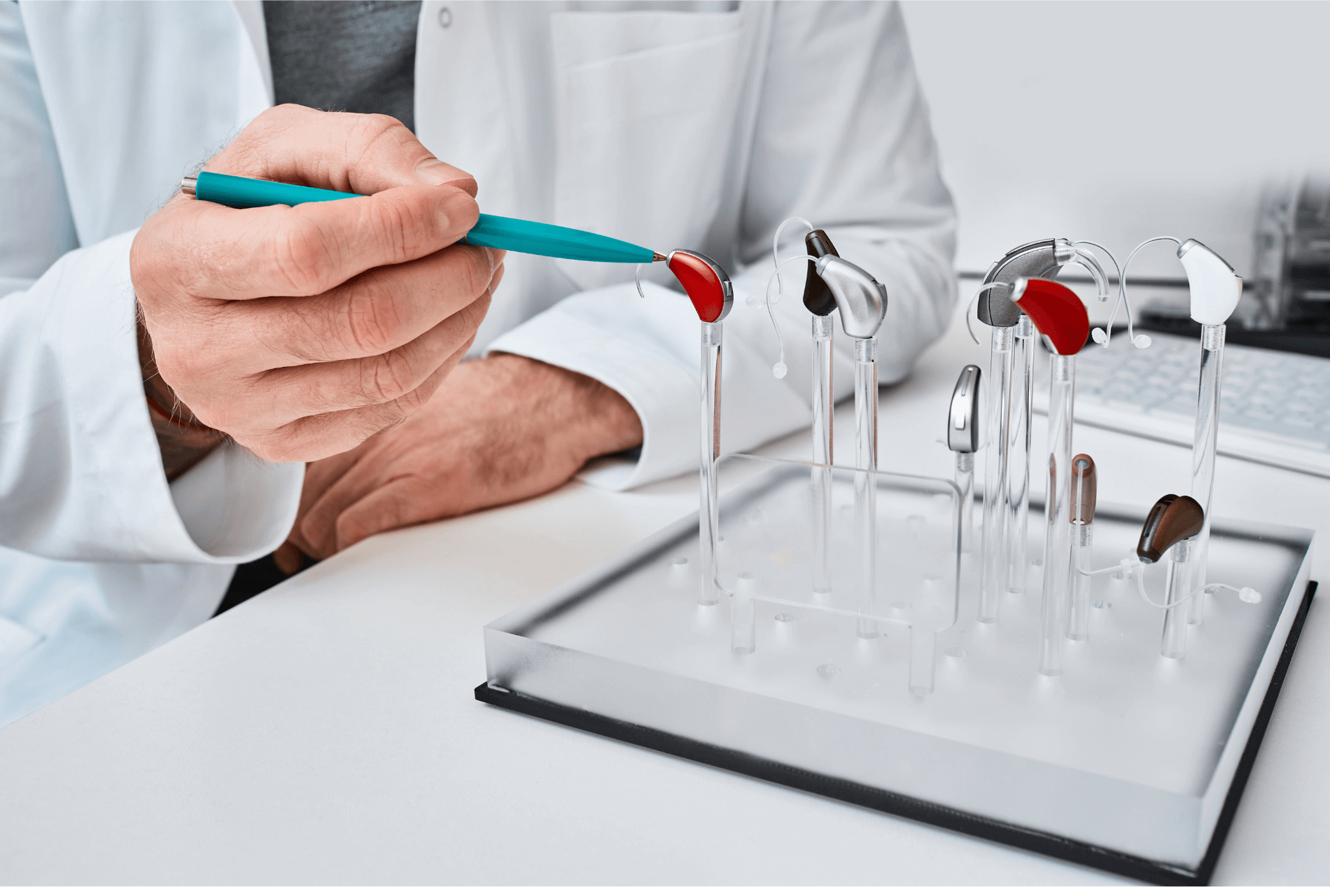Audiologist pointing pen at hearing aid amongst a hearing aid display